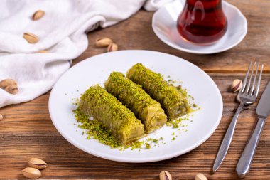 Pistachio baklava. Rolled pistachio baklava on wooden background. Traditional Turkish cuisine. close up