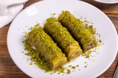 Pistachio baklava. Rolled pistachio baklava on wooden background. Traditional Turkish cuisine. close up