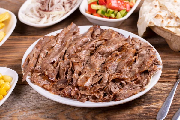 Meat doner kebab on the plate. Turkish meat doner kebab on wooden background. Traditional Turkish cuisine. close up