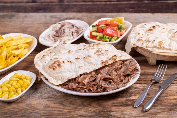Meat doner kebab on the plate. Turkish meat doner kebab on wooden background. Served with hot lavash. Traditional Turkish cuisine. close up