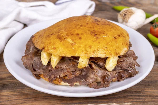 Meat between bread rolls. Meat doner in fat bread on wooden background. Traditional Turkish cuisine. Close-up. local name tombik et doner