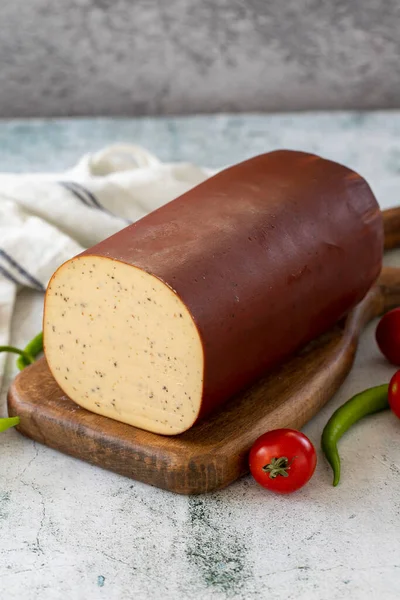 Black Pepper Smoked Cheese. Dutch smoked cheese on stone background. close up