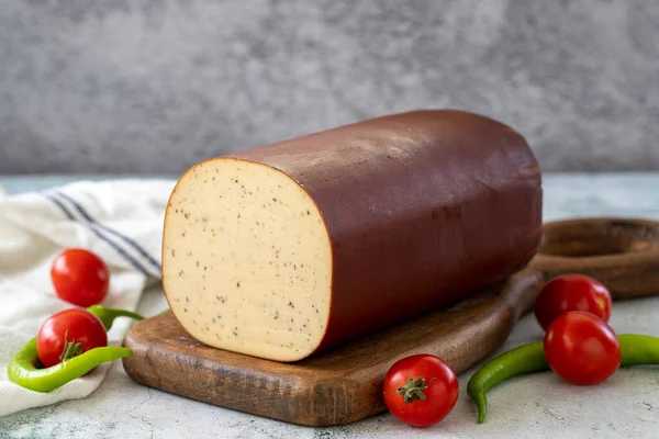 Black Pepper Smoked Cheese. Dutch smoked cheese on stone background. close up