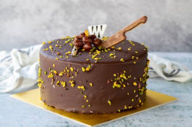Celebration cake with pistachio and chocolate. Birthday cake on gray background. close up