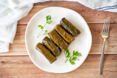 Wrapped leaves with olive oil on a wooden background. Traditional Mediterranean cuisine delicacies. Local name zeytinyagli yaprak sarma or dolmadika. Top view