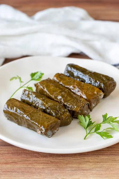 Wrapped leaves with olive oil on a wooden background. Traditional Mediterranean cuisine delicacies. Local name zeytinyagli yaprak sarma or dolmadika. close up