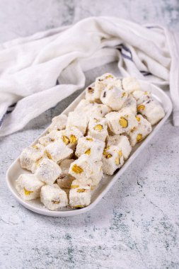 Sütlü Türk yemeği. Fıstıklı Türk Lokumu ve gri arka planda hindistan cevizi. Geleneksel Orta Doğu mutfağı lezzetleri. Kapat.