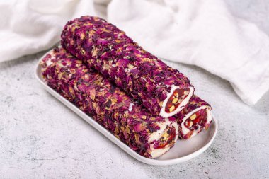 Gri arka planda şam fıstıklı Türk lokumu. Gül yapraklarıyla kaplı Türk lokumu. Yakın plan. Yerel adı Gullu fitil lokum