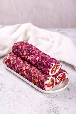 Gri arka planda şam fıstıklı Türk lokumu. Gül yapraklarıyla kaplı Türk lokumu. Yakın plan. Yerel adı Gullu fitil lokum