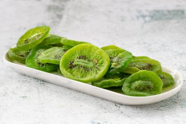 Gri arka planda kurutulmuş kivi dilimi. Gün ışığında kurutulmuş meyve. Kapat.