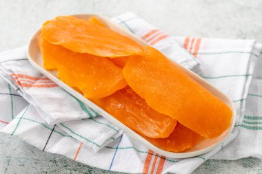 Gri arka planda kurutulmuş mango dilimi. Gün ışığında kurutulmuş meyve. Kapat.