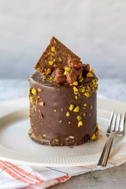 Çikolatalı pasta. Gri arka planda fıstıklı ve çikolatalı pasta. Kapat.