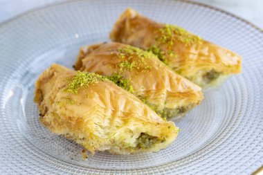 Fıstıklı sobiyet baklava. Geleneksel Akdeniz mutfağı lezzetleri. Gri arka planda üçgen baklava. Kapat.