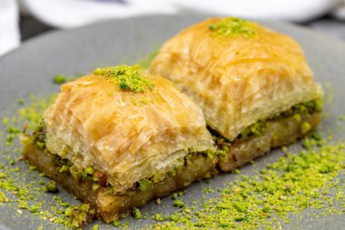 Fıstıklı baklava, koyu arkaplanda. Geleneksel Türk mutfağı lezzetleri. Kapat.