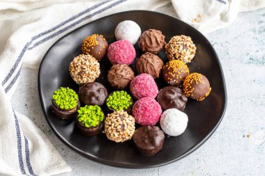 Çikolatalı pralin. Gri arka planda kasedeki çikolataların çeşitliliği. Kapat.