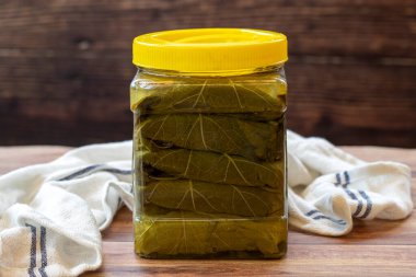 Ahşap arka planda konserve üzüm yaprakları. Yerel adı uzum yapragi