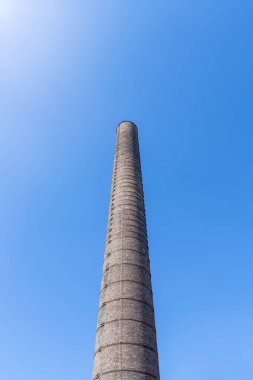 Katowice, Silesia, Polonya 'daki Porselen Fabrikası' nda (Fabryka Porcelany) bulunan uzun, tuğla, endüstriyel baca mavi, bulutsuz gökyüzüne karşı. 