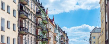 Polonya, Nysa 'daki apartmanlara bakış açısı yaz ve güneşli bir günde. Süslü cephelerdeki dekoratif pencereler ve balkonlar mavi, bulutlu gökyüzüne karşı.