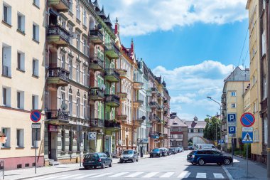 Nysa, Polonya - 11 Haziran 2022: Güneşli bir yaz gününde Polonya 'nın Nysa kentindeki konutlara perspektif bakış. Süslü cephelerdeki dekoratif pencereler ve balkonlar mavi, bulutlu gökyüzüne karşı.