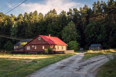 A beautiful sunset in a small village bordering the forest. A small country house illuminated by the sun. Krasnobrod, Poland