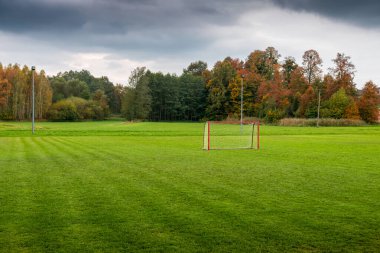 Kırsal bir sonbahar manzarasında futbol antrenman sahası. Kusursuz budanmış yemyeşil çimenler.