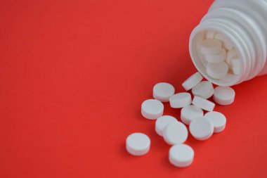 Kırmızı arka plana dağılmış beyaz tabletler.