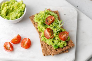 Avokado dilimleri, domatesler ve siyah susam tohumlu sağlıklı kahvaltı ekmeği..
