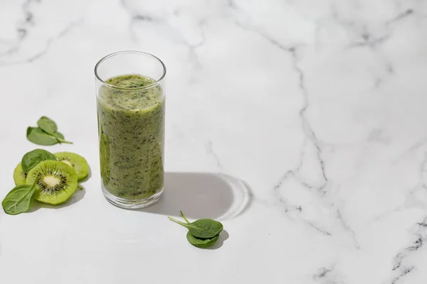 Bir bardak kivi ve gün ışığında ıspanak dilimlenmiş yeşil smoothie.