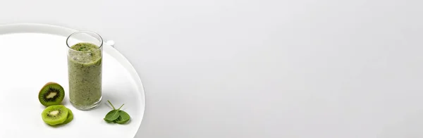 Banner Green smoothie bir bardak kivi dilimleri ve gün ışığında ıspanak. Beyaz tablo