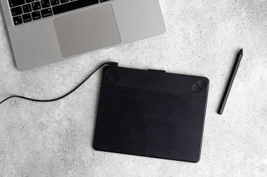 Grafik tablet, kalem ve dizüstü bilgisayarı olan bir iş yeri. Üst Manzara. Gri arkaplan