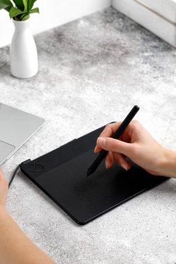 Eller masada otururken grafik tablet ve dizüstü bilgisayar kullanıyor. Proje üzerinde çalışıyorum. Mesafeli iş. Tasarımcı veya fotoğrafçı