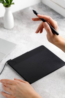Eller masada otururken grafik tablet ve dizüstü bilgisayar kullanıyor. Proje üzerinde çalışıyorum. Mesafeli iş. Tasarımcı veya fotoğrafçı