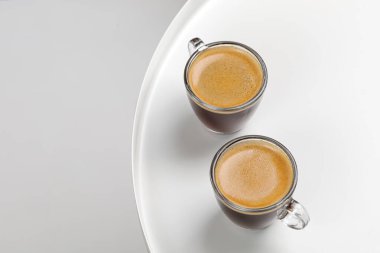 Sabah beyaz masada iki bardak kahve fincanı ve espresso. Aroma, ristreto. Bir fincan kahve. Bardak. Kapat, üst görünüm