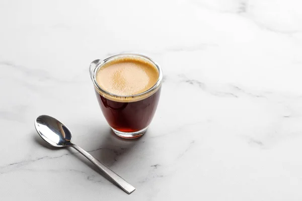 Sabah bir bardak kahve fincanı espresso ile beyaz mermer arka planda kaşık ile. Aroma, ristreto. Bir fincan kahve. Kapat.