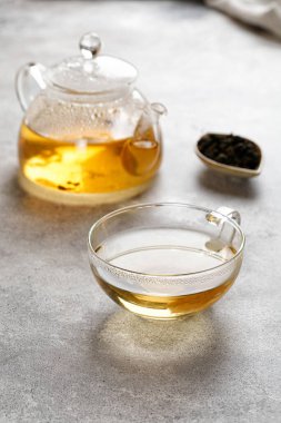 Yeşil bitki çaylı bir kupa ya da kupa ve gri arka planda çay yapraklı bir çaydanlık. Güzellik rengi