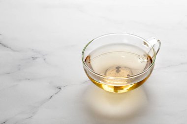 Beyaz mermer arka planda yeşil bitki çayı olan bir fincan ya da kupa. Minimalizm.