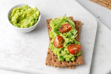 Avokado dilimleri, domatesler ve siyah susam tohumlu sağlıklı kahvaltı ekmeği..