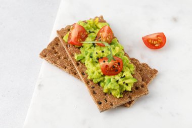 Avokado ezmeli ekmek, tomaro ve roka. Kapat.