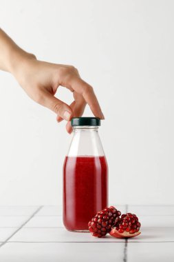 Şişe içinde nar suyu ve şişenin tepesine dokunmak. Fayans zemininde taze sıkılmış meyve suyu. Vitaminler.