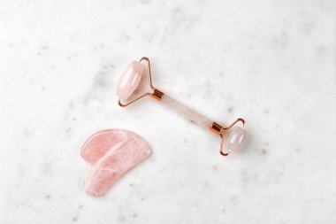 Mermer arka planda patenli yüz masajı. Pembe gül kuvarsı. Yaş karşıtı, ürün kaldırma.