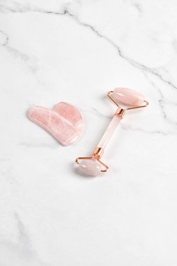 Mermer arka planda patenli yüz masajı. Pembe gül kuvarsı. Yaş karşıtı, ürün kaldırma.