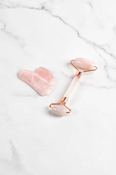 Mermer arka planda patenli yüz masajı. Pembe gül kuvarsı. Yaş karşıtı, ürün kaldırma.