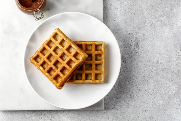 Waffle beyaz tabakta boş ve mermer tahtada çikolata ezmesi. Üst görünüm