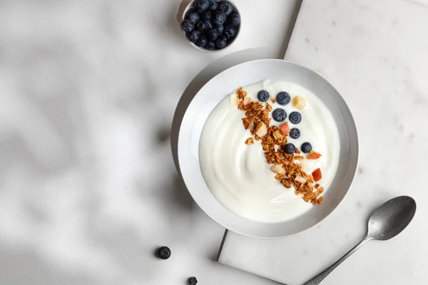 Beyaz yoğurtlu lezzetli sağlıklı kahvaltı kasesi granola ya da müsli ile taze yaban mersini. Üst görünüm