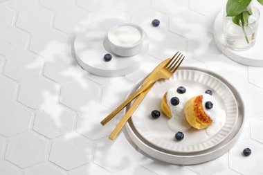 Güneşli bir günde gerçek hayat, fayans üzerinde kahvaltı fikri. Tabakta tatlı, altın sofra takımı.