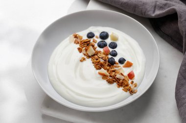Müsli, granola, yoğurt ve yabanmersinli sağlıklı doğa kahvaltısı, beyaz arka plan..