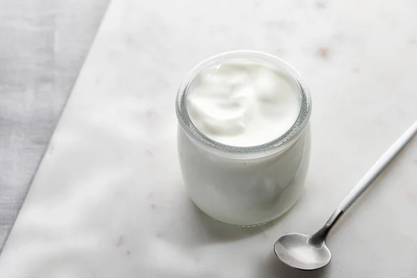 Cam kavanozda içi boş beyaz yoğurt mermer tahtada kaşıkla. Basit ve minimalist
