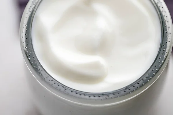 Greek yogurt in a glass jar. Close up, top view. Tasty yogurt Wave of white yogurt