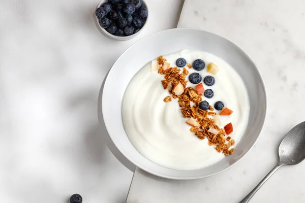 Beyaz yoğurtlu lezzetli sağlıklı kahvaltı kasesi granola ya da müsli ile taze yaban mersini. Üst görünüm