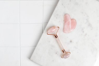 Gül kuvars masaj aleti ve mermer tahtada guache kazıyıcı ve fayans arka planı